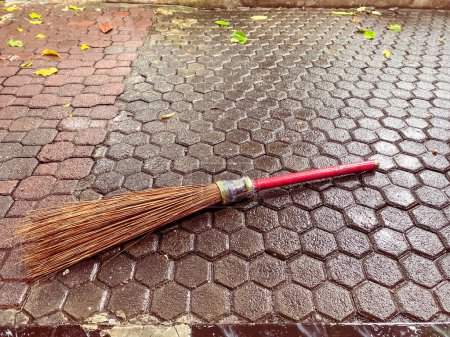 Stick broom on wet paving blocks floor. Coconut leaf broomstick rough duster sweeper (with clipping path)