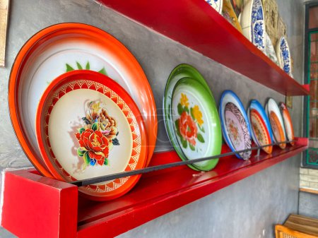 Téléchargez les photos : Assiettes, plateaux et vasques aux motifs old school utilisés comme décoration murale dans un restaurant de Jakarta - en image libre de droit