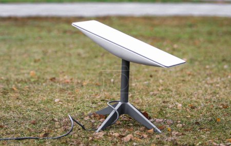 Téléchargez les photos : Une antenne pour recevoir le signal Internet depuis l'espace Starlink au sol dans le parc - en image libre de droit