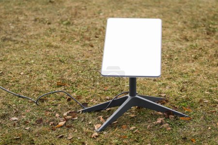 Foto de Una antena para recibir la señal de Internet desde el espacio Starlink en el suelo en el parque - Imagen libre de derechos