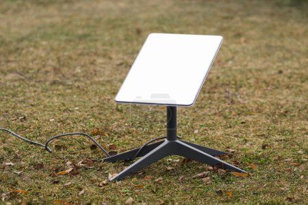 Eine Antenne für den Empfang des Internetsignals aus dem Weltraum Starlink auf dem Boden im Park