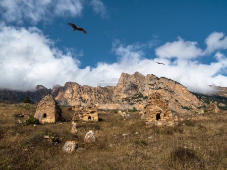 Téléchargez les photos : Grave stone city under a big rock. Old stone tomb, a crypt on the top of a mountain. Ossetia region. - en image libre de droit