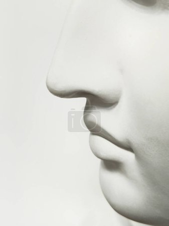 Nose and mouth on a light gray background, side view. Close-up of a humanoid face. Grey abstract male nose. Vertical view.