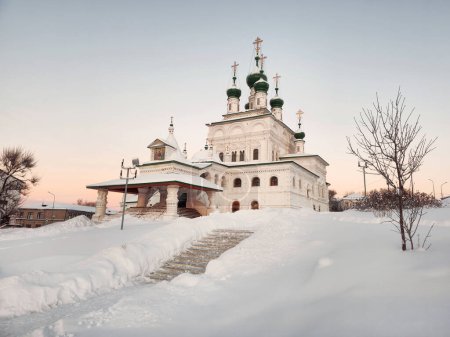 White snow around the Holy Trinity Cathedral Solikamsk (Russia). Majestic white-stone famous church in the old Ural city on a winter evening. Staircase cleared of snow to the temple.