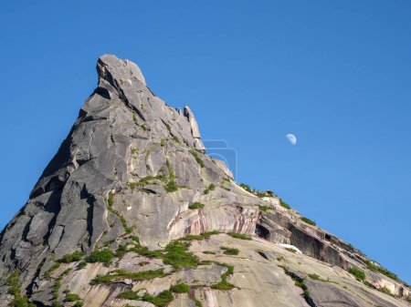 Téléchargez les photos : Lune sur le rocher pointu. Roche avec un sommet pointu. Paysage estival avec roche et ciel bleu. - en image libre de droit