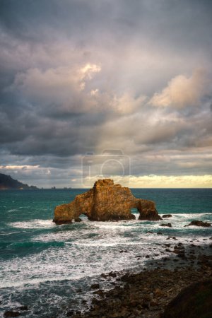 Téléchargez les photos : Les rayons du soleil levant illuminent brièvement les nuages au-dessus de l'arche en pierre de Penafurada à Loiba à Cabo Ortegal Géoparc Unesco Corogne Galice - en image libre de droit