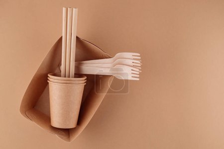 Eco-friendly disposable tableware. Kraft paper food containers, cups and forks on beige background. Zero waste and plastic free concept. Copy space
