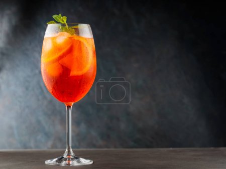 Aperol Spritz Cocktail mit Orange und frischer Minze auf dunklem Hintergrund. Glas Aperol Spritz Cocktail mit Eiswürfeln. Kopierraum