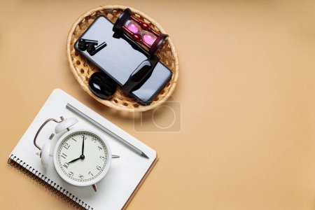 Photo for Turned off Electronic Gadgets, Alarm Clock and Notepad on Beige Background, Time Management and Digital Detox Concept - Royalty Free Image