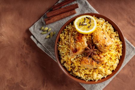 Indian Chicken Biryani with Aromatic Spices in Bowl on Brown Background, Copy Space, Top View