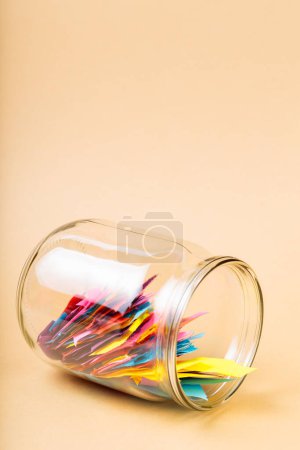 Glass Jar Filled with Colorful Paper Scraps on Beige Background, Concept of Reducing Paper Waste Through Recycling