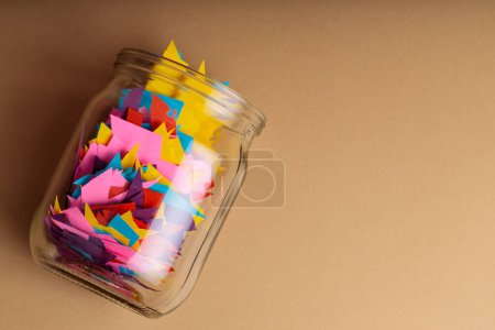 Glass Jar Filled with Colorful Paper Scraps on Beige Background, Concept of Reducing Paper Waste Through Recycling