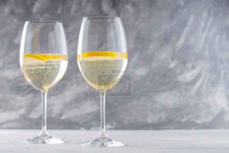Cocktail tendance Elderflower Hugo Spritz avec tranche de citron sur fond de béton gris, Espace de copie
