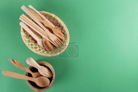 Wooden Kitchen Utensils Collection in Wicker Basket on Green Background, Top View, Copy Space