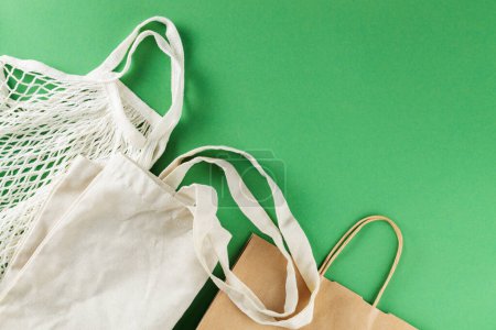 Cotton and Paper Bags on Green Background, Sustainable Zero Waste Lifestyle Concept