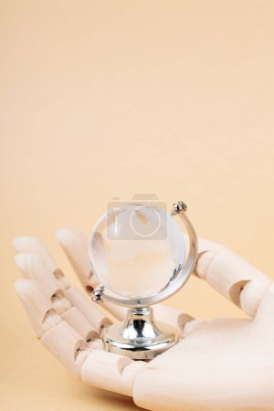 Globe de verre dans la paume de Cyborg sur fond beige, concept de protection technologique contre les catastrophes environnementales