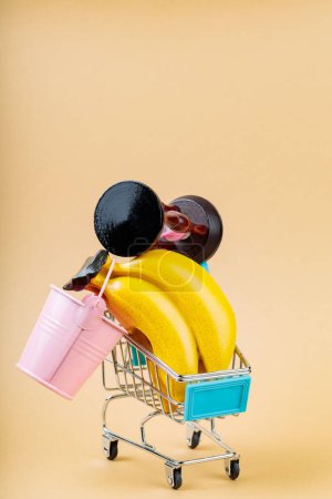 Overfilled Shopping Cart on Beige Background, Overconsumption Concept, Copy Space