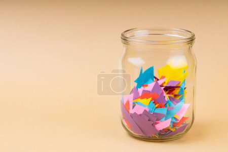 Glass Jar Filled with Colorful Paper Scraps, Reducing Paper Waste Concept, Copy Space
