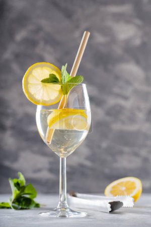 Hugo Spritz Cocktail mit Minze, Zitrone und Bambusstroh auf Betongrund