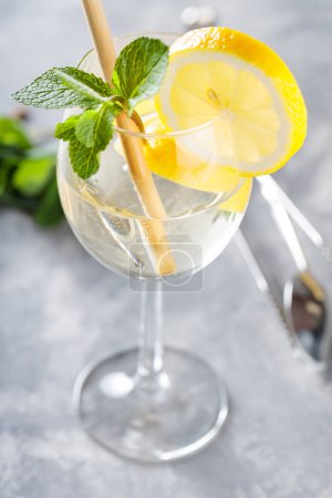 Hugo Spritz Cocktail with Mint, Lemon and Bamboo Straw on Concrete Background
