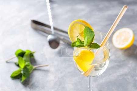 Hugo Spritz Cocktail with Mint, Lemon and Bamboo Straw on Concrete Background