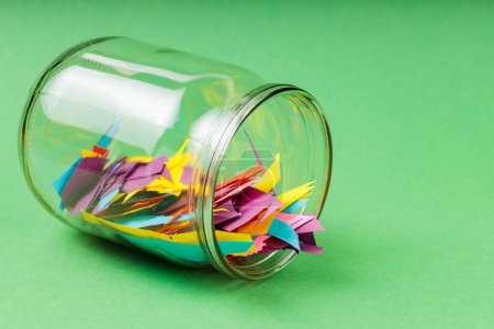 Glass Jar with Colorful Paper Scraps on Green Background, Recycling Concept