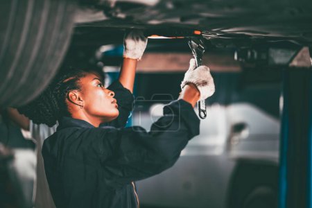 Photo for Garage women worker mechanic team working car auto service fix replace  under car lift hoist - Royalty Free Image