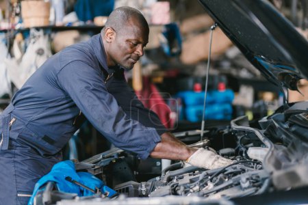 Photo for Garage Mechanic African Black male professional working car auto service checking engine oil - Royalty Free Image