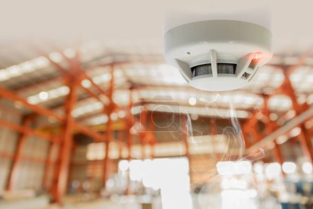 Téléchargez les photos : Alarmes incendie pour détecteur de fumée d'entrepôt Installation du dispositif de sécurité du détecteur d'incendie au plafond de la zone de stockage de fret - en image libre de droit
