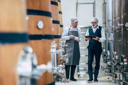 Enólogo que trabaja en la fábrica moderna de vinos grandes bebidas alcohólicas calidad de la industria y el monitor de fermentación
