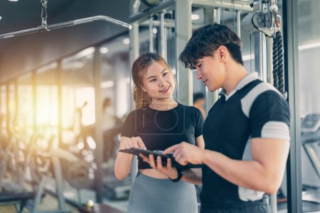 Photo for Fitness personal trainer talking with healthy lady customer about workout list weight training programs at the gym sport club - Royalty Free Image