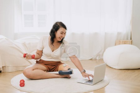 Photo for Prosthetic leg woman healthcare sport training online exercise activity. healthy disability people laptop working lifestyle at home. prostheses people with leg amputations weight lifting. - Royalty Free Image