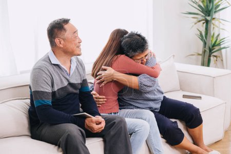 Teenager Mädchen Tochter Umarmung Mutter sitzt mit Eltern zu Hause für Trost Pflege Liebesausdruck in asiatischen Familie