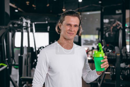 Téléchargez les photos : Homme de sport sain avec bouteille de shaker de lactosérum. protéines de lactosérum heureux pour le gain de masse musculaire de force et repas de boisson faible en gras dans la forme physique de gymnase - en image libre de droit