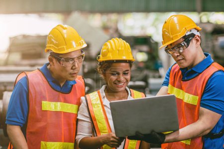 Téléchargez les photos : Ingénieur ouvrière femme avec équipe masculine travaillant ensemble dans l'usine en regardant ordinateur portable sourire heureux. - en image libre de droit