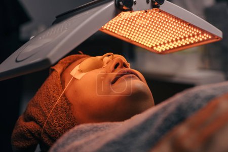 Téléchargez les photos : Processus cosmétique facial femme avec biolight LED laser visage traitement de la peau réparation lifting rajeunissement dans la technologie beauté spa - en image libre de droit