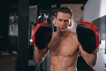 Photo for Kickboxing athlete trainer portrait with boxing pad glove in fitness gym sport action - Royalty Free Image