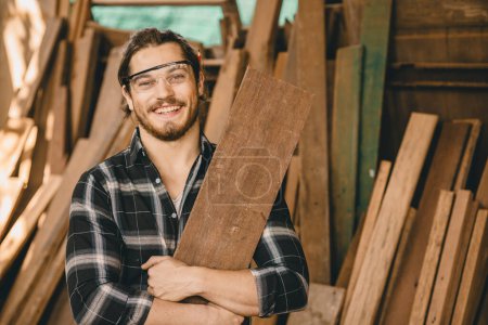 Photo for Portrait young carpenter artisan hand wood crafting man with wooden panel happy smiling - Royalty Free Image