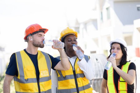 Photo for Healthy worker engineer team thirsty drinking clean water in hot temperature weather summer season for fresh relax at construction site workplace. - Royalty Free Image