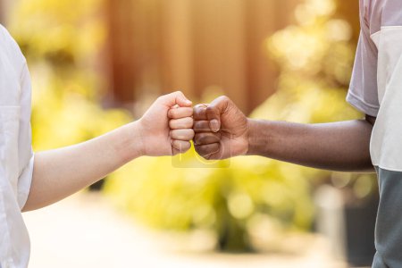 black and white people hand fist bump together to greet friends in modern teenagers.