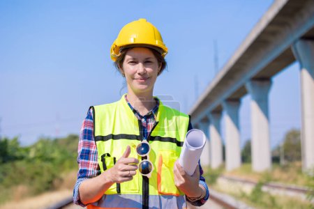 Portrait engineer women on railway tracks construction site with blueprint roll working project manager in suburb transportation line
