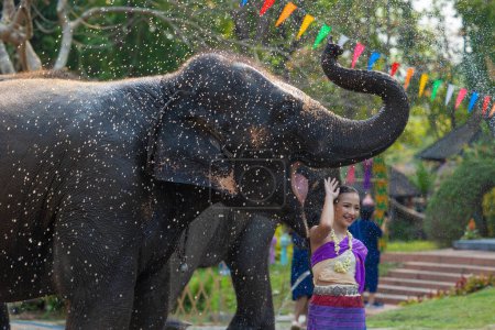 Téléchargez les photos : Festival de Songkran. Peuple thaïlandais du Nord en vêtements traditionnels s'habiller éclaboussant l'eau ensemble dans le festival culturel de jour de Songkran avec l'éléphant. - en image libre de droit