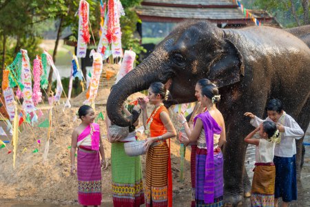 Photo for Songkran festival. Northern Thai people in Traditional clothes dressing splashing water together in Songkran day cultural festival with elephant background. - Royalty Free Image