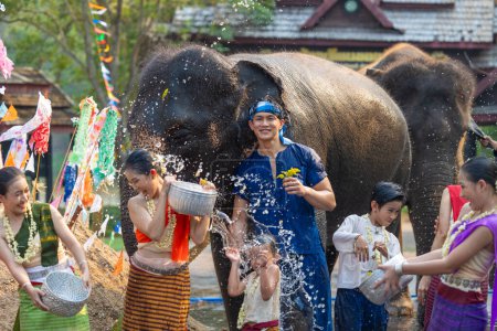 Photo for Songkran festival. Northern Thai people in Traditional clothes dressing splashing water together in Songkran day cultural festival with elephant background. - Royalty Free Image