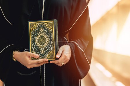 Photo for Holy Quran book cover with arabic calligraphy translate meaning of Al Quran. Closeup Arab people hand holding Quran muslim book. - Royalty Free Image