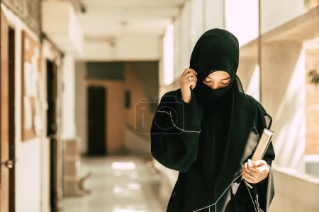 Photo for Muslim niqab woman read and learning the Quran and faith The Holy Al Quran book. Arab saudi black chador lady. - Royalty Free Image