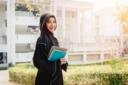 Universität saudi muslimischen Niqab Frau High Education auf dem Universitätscampus glücklich lächelnd mit modernem Wissensbuch. Arabische saudi schwarz chador lady.