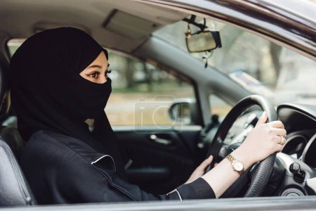 Photo for Saudi muslim women driving a car. Modern arab lady drive automotive vehicle. - Royalty Free Image