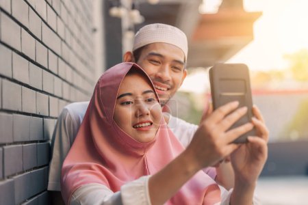 Photo for Muslim people teen happy play smartphone relax enjoy together. islamic using cell phone outdoors - Royalty Free Image