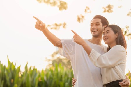 Photo for Couple teen standing happy smiling together park outdoors sun shining hand pointing high for life planning future insurance business vision concept - Royalty Free Image